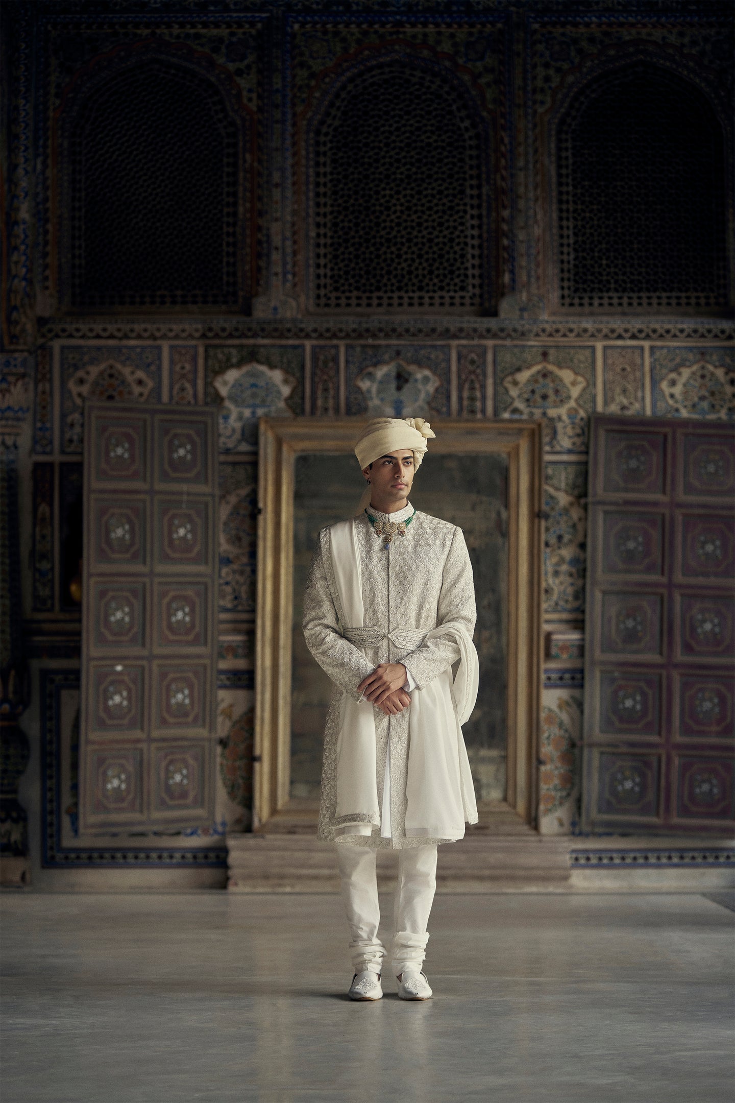 IVORY RAW SILK SHERWANI WITH KURTA AND CHURIDAR WITH AN OPTIONAL WORKED STOLE AND BELT AND EMBROIDERED JUTIS.