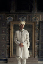 Load image into Gallery viewer, IVORY RAW SILK SHERWANI WITH KURTA AND CHURIDAR WITH AN OPTIONAL WORKED STOLE AND BELT AND EMBROIDERED JUTIS.
