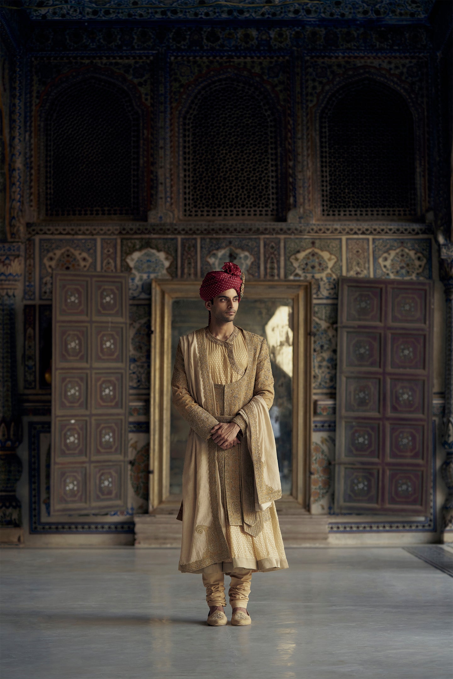 GOLD MATKA SILK ANGRAKHA STYLE SHERWANI WITH A CHANDERI BOOTI CHOGA AND CHURIDAR. IT HAS AN OPTIONAL BELT , STOLE AND WORKED JUTIS